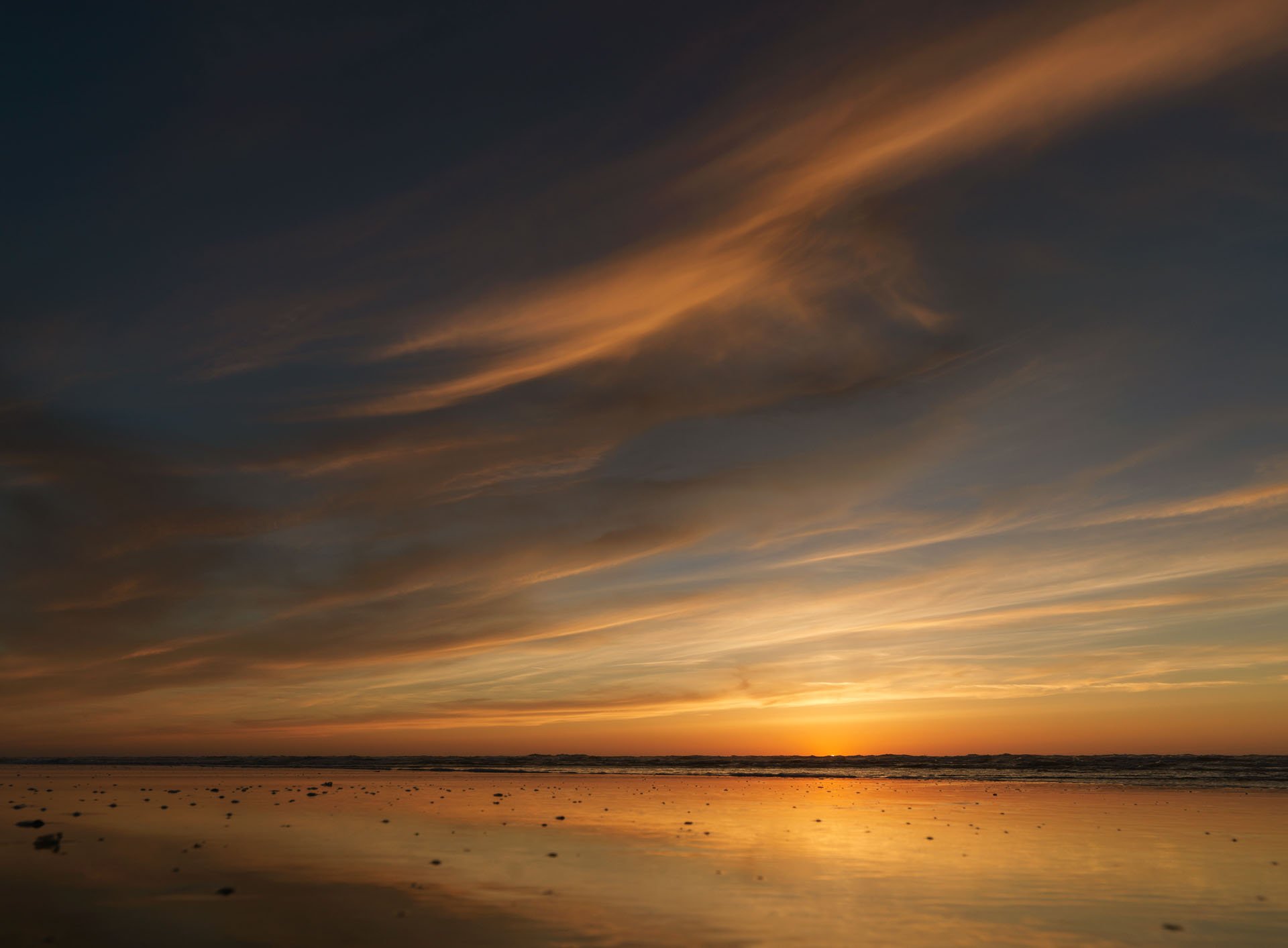Streaks of orange cloud over the beach at sunset