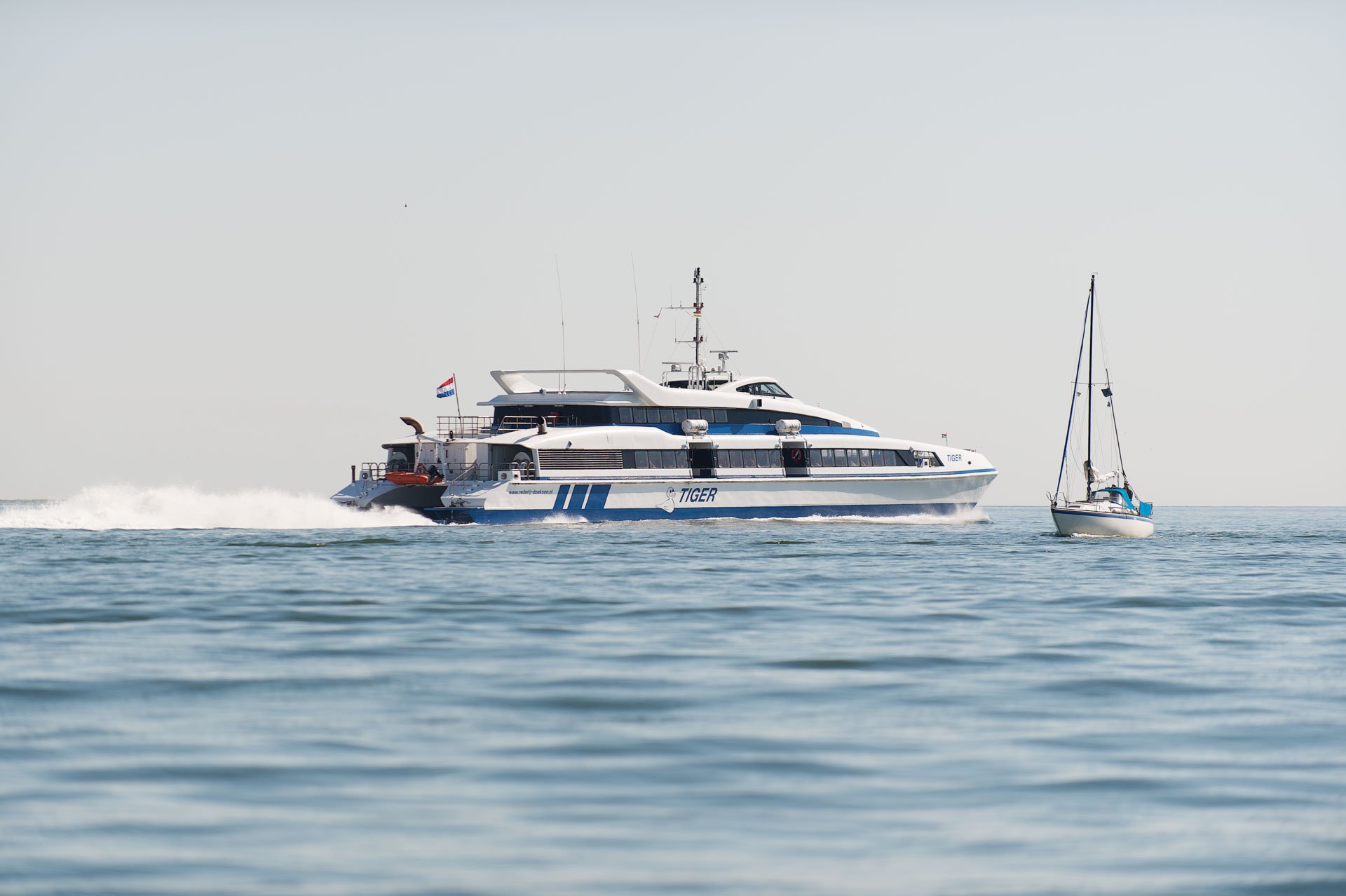Passenger ferry and sailboat on calm water