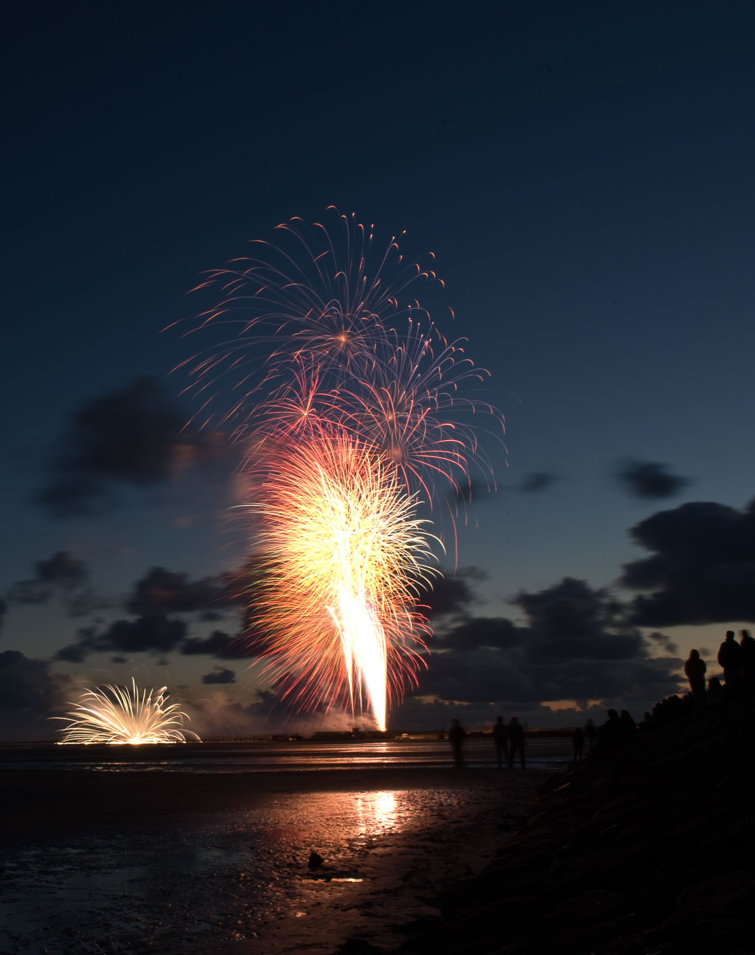 Fireworks rising above the beach at dusk